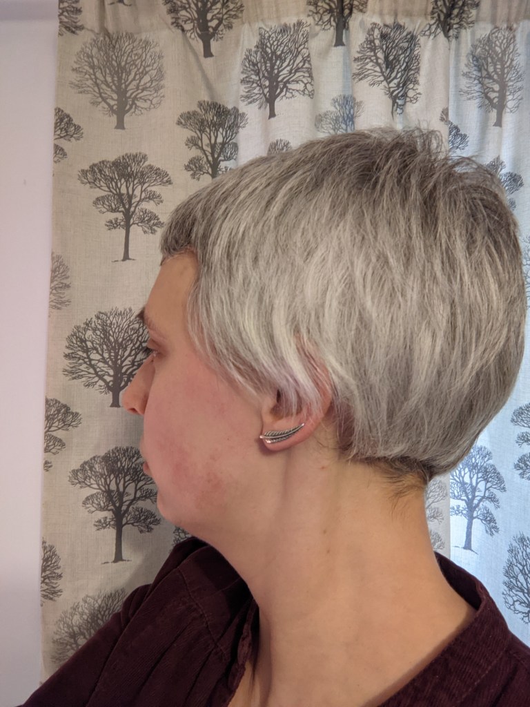 A woman with short grey hair, looking away from the camera