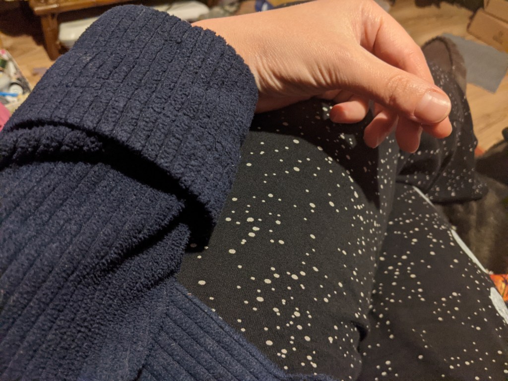 a woman's hand and arm, wearing a navy blue dressing gown with the cuff turned up