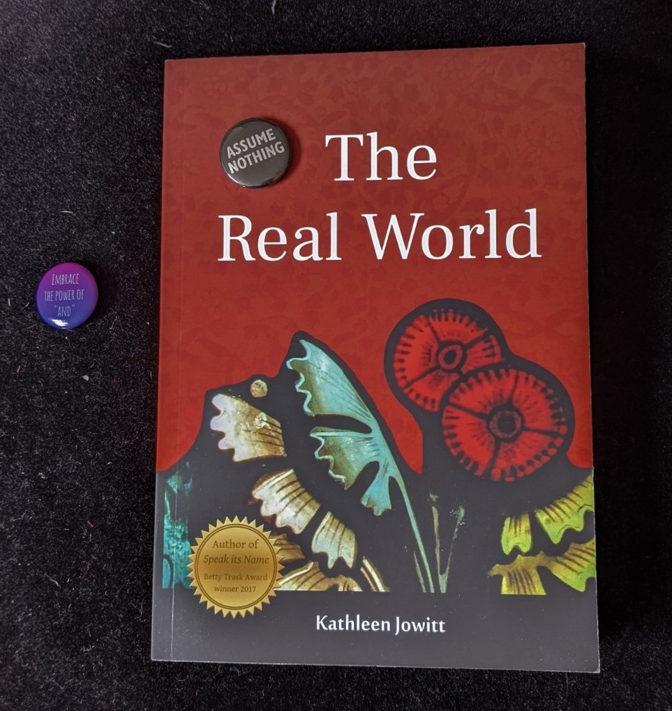 'The Real World' with two pin badges, one reading 'EMBRACE THE POWER OF "AND"' and the other, 'ASSUME NOTHING'
