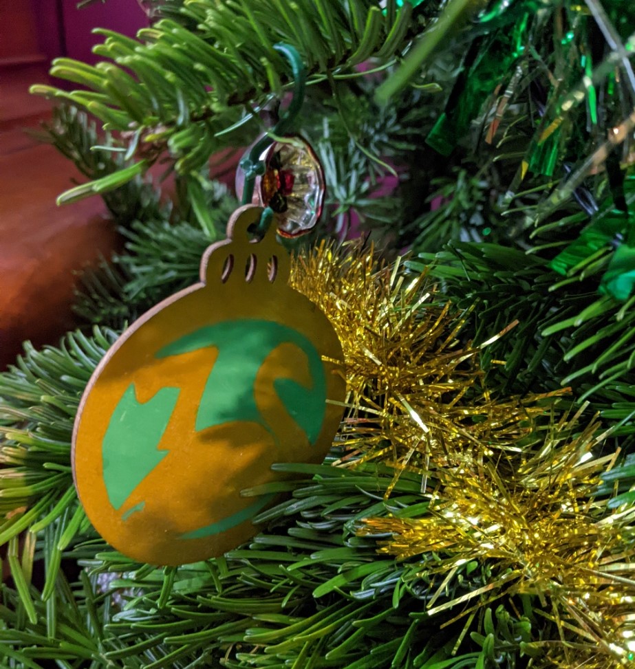 A flat wooden Christmas tree decoration with a swan and the figure 7 in gold on a green background