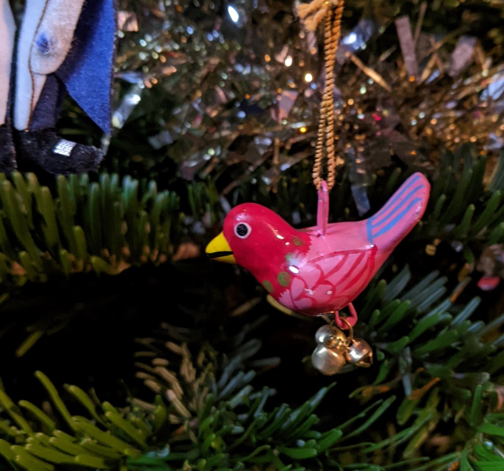 Christmas tree decoration representing a small pink bird, with tiny metal bells dangling from its feet