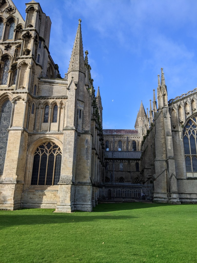 A waning gibbous moon in a stretch of blue sky between ornate pinnacles in pale grey stone