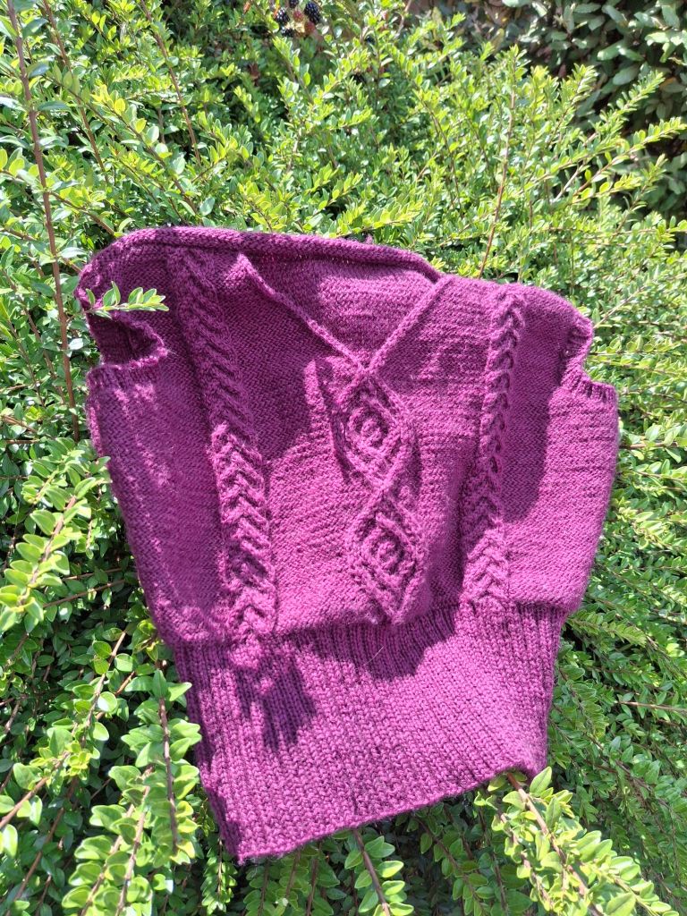 A bright purple knitted sleeveless top with a cable pattern