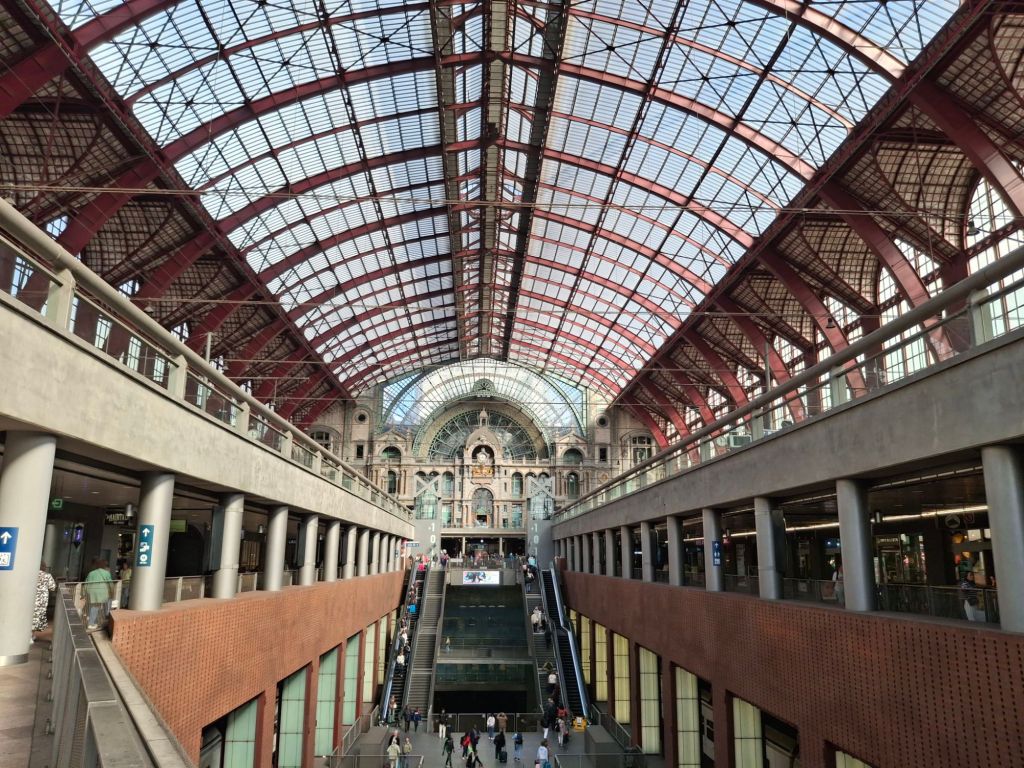 A railway station. At the centre of the image, in the distance, is a neo-Romanesque facade.
